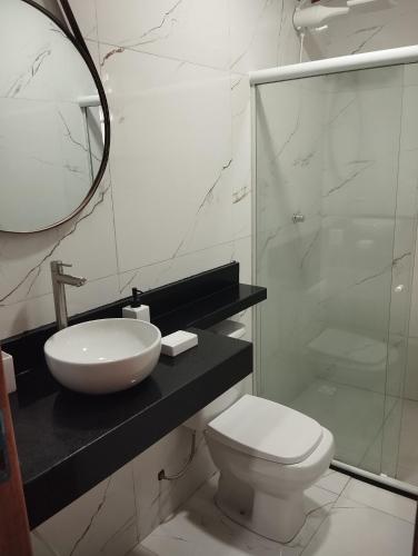 a bathroom with a sink and a toilet and a mirror at 05 minutos da praia - Casa Superior céu azul Buzios in Búzios