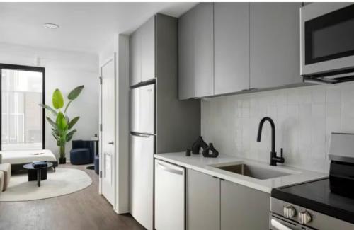 a white kitchen with a sink and a refrigerator at Modern Tampa Studio Near Ybor City & Downtown in Tampa