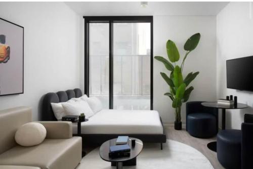a white living room with a couch and a table at Modern Tampa Studio Near Ybor City & Downtown in Tampa