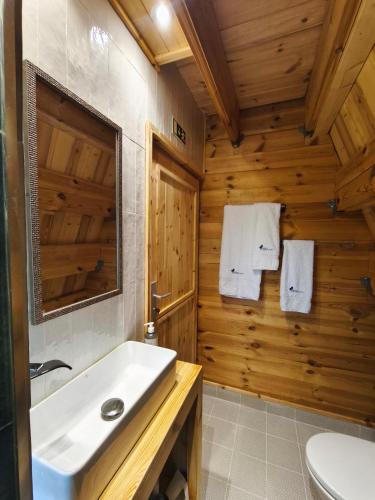 ein Badezimmer mit einem weißen Waschbecken und einer Holzwand in der Unterkunft Chalé da Cumieira Nova in Seia