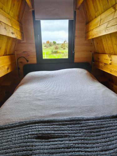 Bett in einem kleinen Zimmer mit Fenster in der Unterkunft Chalé da Cumieira Nova in Seia