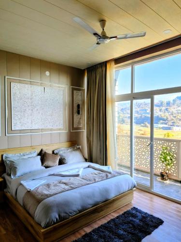 a bedroom with a large bed and a large window at Sunrise Vista Resort & Hotel in Bāgeshwar
