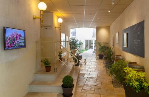a hallway with stairs and potted plants in a building at BRIT HOTEL Le Lion d'Or CHINON in Chinon