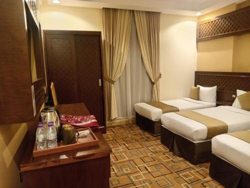 a hotel room with two beds and a table at فندق الكشاف المتقدم توصيل للحرم مجاني in Mecca