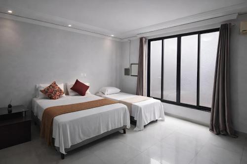 a white room with two beds and a large window at Casa Faya Foz in Foz do Iguaçu