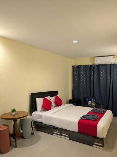 a bedroom with a bed with red pillows and a table at Number 1 Guesthouse in Ao Nang Beach