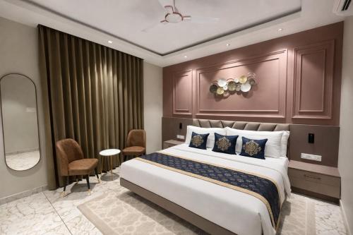 een hotelkamer met een groot bed en stoelen bij Ocean Regency in Ujjain