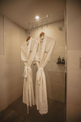 a rack of white towels hanging in a bathroom at Étoile du Lac Lyster - Spa & Vue sur le Lac in Coaticook