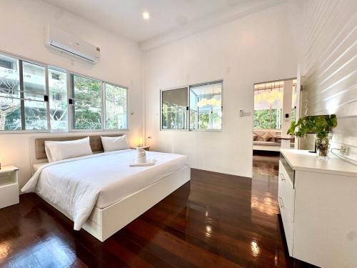 a white bedroom with a large bed and windows at Sunset Beach Villa 30m to Beach 4BR in North Pattaya