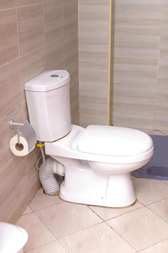 a bathroom with a white toilet in a room at Kj suites in Meru