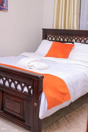 a wooden bed with an orange and white blanket at Kj suites in Meru