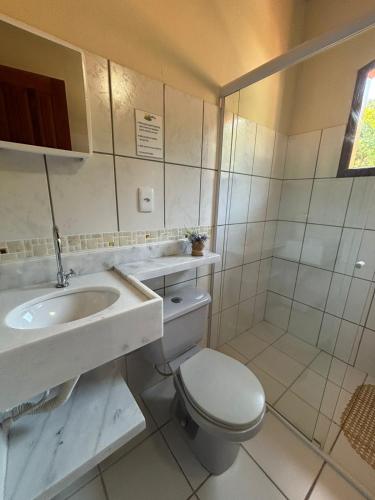 a white bathroom with a toilet and a sink at FLATS e SUÍTES NATIVA in Paraty