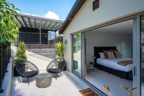 a bedroom with a bed and chairs on a balcony at Limerick- Fire Place- Lake Views- BBQ- AC in Queenstown