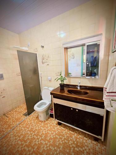 a bathroom with a toilet and a sink and a window at Hostel La Casa de Mabel in Natal
