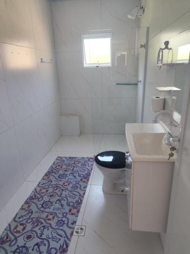 a bathroom with a toilet and a sink and a rug at Casa Aconchegante in Bertioga