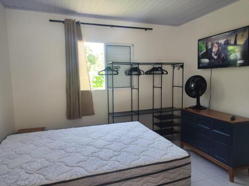 a bedroom with a bed and a dresser and a window at Casa Aconchegante in Bertioga