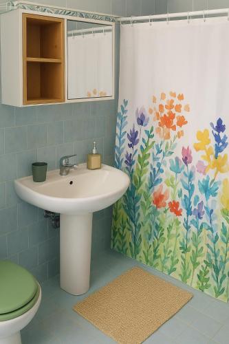 a bathroom with a sink and a flower shower curtain at Alabianca in Villa Vela