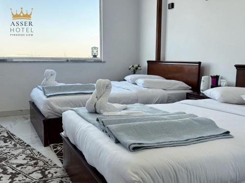 a room with three beds with towels on them at NEW ASSER HOTEL PYRAMID in Cairo