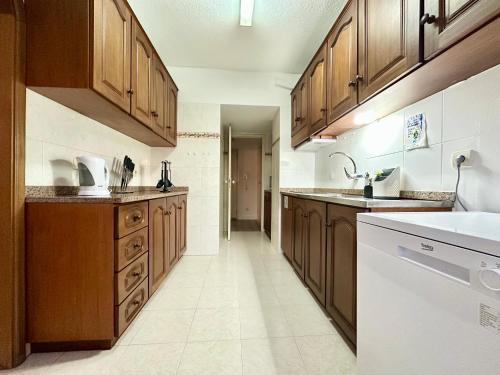 una cucina con armadi in legno e un apparecchio bianco di Santa Luzia pokoje a Funchal