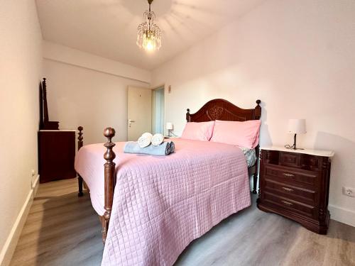 una camera da letto con un letto con lenzuola rosa e un comò di Santa Luzia pokoje a Funchal