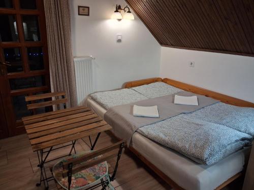 een slaapkamer met twee bedden en een tafel en een stoel bij Vagabund Vendégház in Etyek