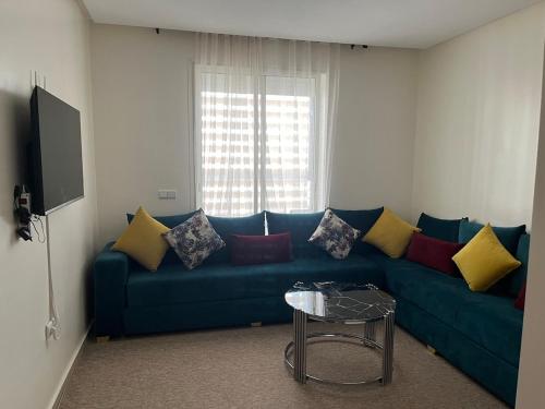 een woonkamer met een blauwe bank en kleurrijke kussens bij Apartment in a residence with pool in Mohammedia