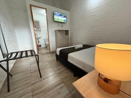 Un dormitorio con una cama y una silla y un televisor. en Hotel CSI Llanogrande, en Rionegro