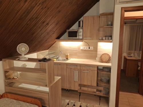 een kleine keuken met houten kasten en een spoelbak bij Vagabund Vendégház in Etyek