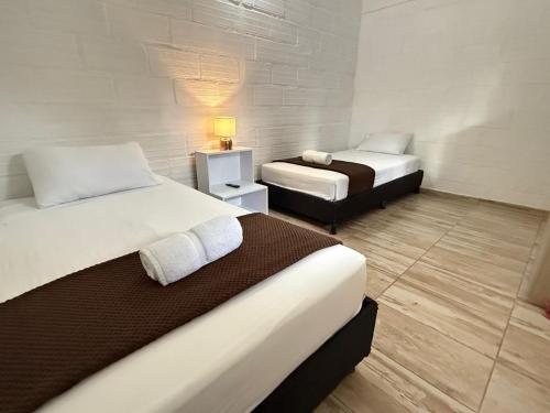 Una habitación de hotel con dos camas y una lámpara. en Hotel CSI Llanogrande, en Rionegro