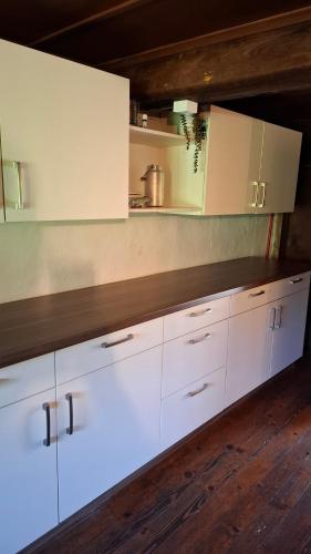 a kitchen with white cabinets and a wooden floor at Ferienhütte See 4 in Seeberg