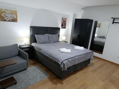 a bedroom with a bed with a chair and a mirror at Apartman Good Night in Surčin
