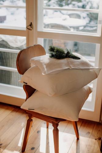 a pile of pillows on a chair in front of a window at Willa Tyrolczyk in Karpacz
