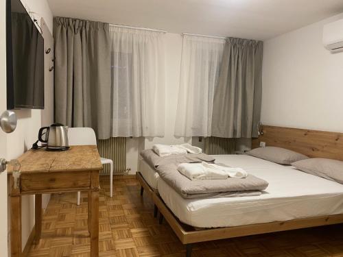 1 Schlafzimmer mit 2 Betten, einem Tisch und einem Fenster in der Unterkunft Dolomiti Lodge - Fit & Well in Belluno