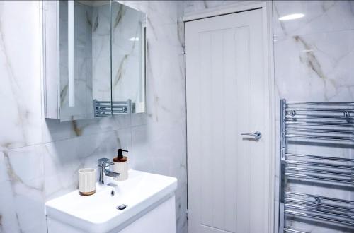 a white bathroom with a sink and a shower at Cosy Luxe Manchester Home With Fresh Bakes in Manchester