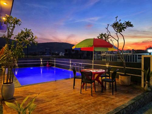 een terras met een tafel, stoelen en een parasol bij ll EMPYREAN STAYS ll G0DFATHER VILLA ll MINI PUB ll 4BHK ll AC ll LARGEST POOL ll in Lonavala