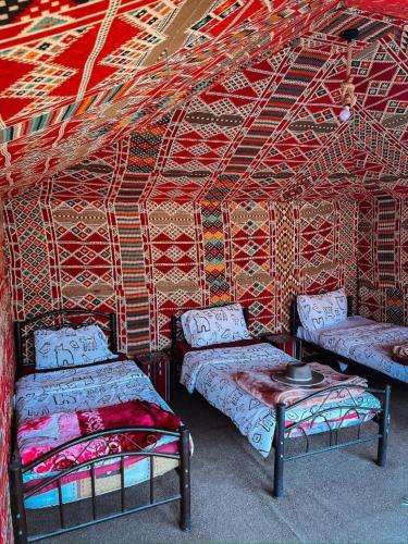 a room with two beds and a table in it at Wadi Rum Bedoun in Wadi Rum