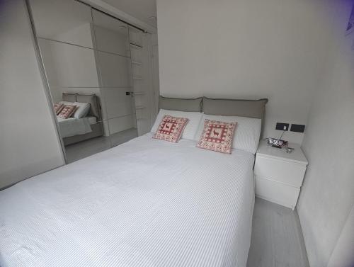 a bedroom with a white bed with two pink pillows at Relax Mountain Apartments in Isolaccia
