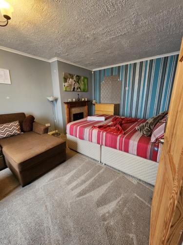een slaapkamer met een bed en een bank bij The Rushdon in Grays Thurrock
