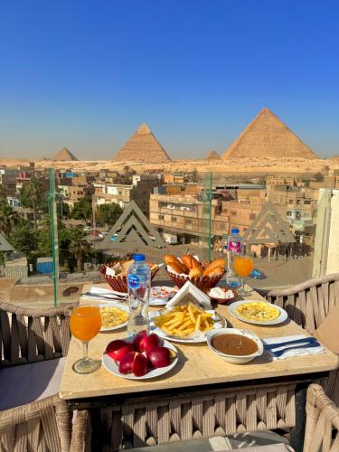 einen Tisch mit Nahrung und Pyramiden im Hintergrund in der Unterkunft Aida's Pyramids Hotel in Kairo