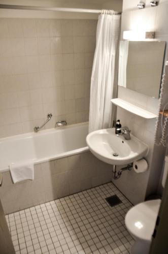 a bathroom with a sink and a tub and a toilet at Hotel Rössle in Schongau