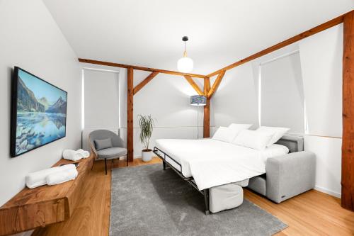a bedroom with a white bed and a chair at La Suite du Bourg in La Tour-de-Peilz