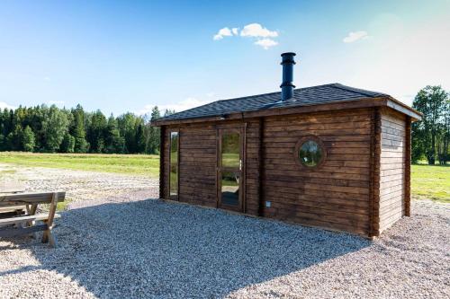 Ein kleines Holzgebäude auf Kies neben einer Bank in der Unterkunft Cope un Pirts in Yumprava