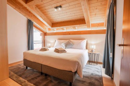 a bedroom with a large bed with a wooden ceiling at Turuwang Penthouse by HomeFlow in Zermatt
