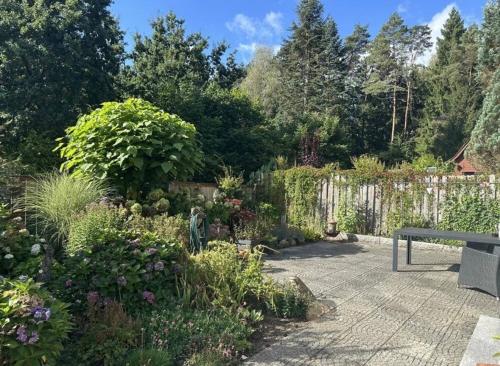 einen Garten mit einer Bank, Blumen und einem Zaun in der Unterkunft Waldgeflüster in Buchholz in der Nordheide