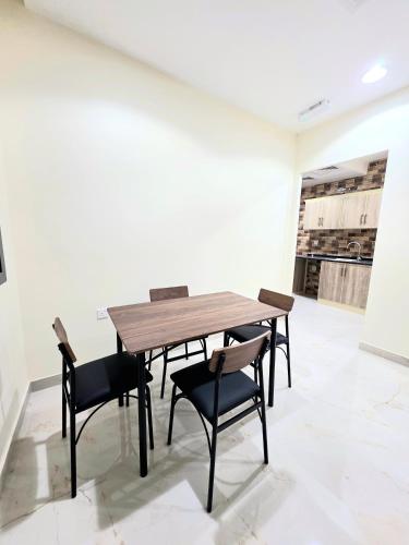 a wooden table and chairs in a white room at RAK Corniche Stay Home in Ras al Khaimah