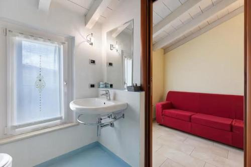 bagno con lavandino e divano rosso di Residenza Amé Peschiera del Garda a Peschiera del Garda