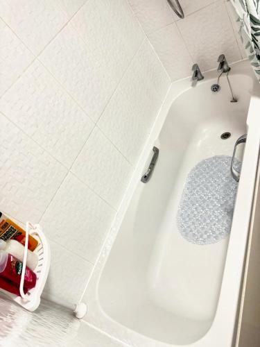 a white bath tub with a basket next to it at Stylish MK Flat in Milton Keynes