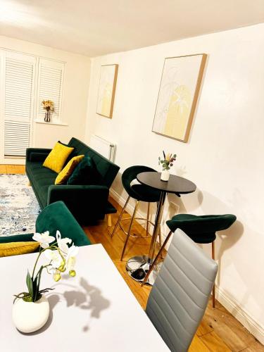 a living room with a green couch and a table at Stylish MK Flat in Milton Keynes