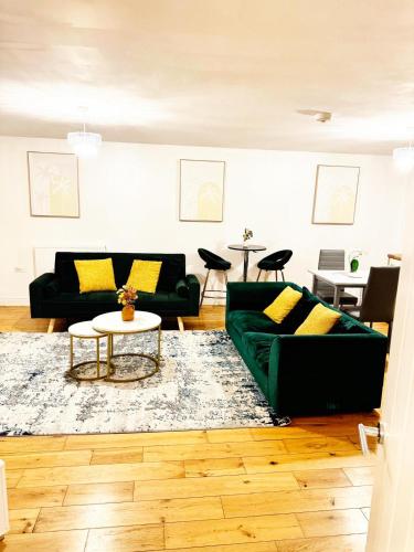 a living room with two green couches and a table at Stylish MK Flat in Milton Keynes