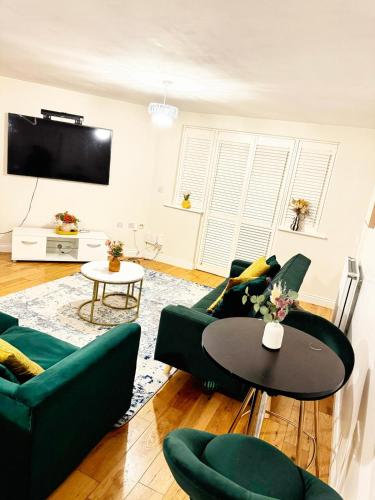 a living room with green furniture and a table at Stylish MK Flat in Milton Keynes